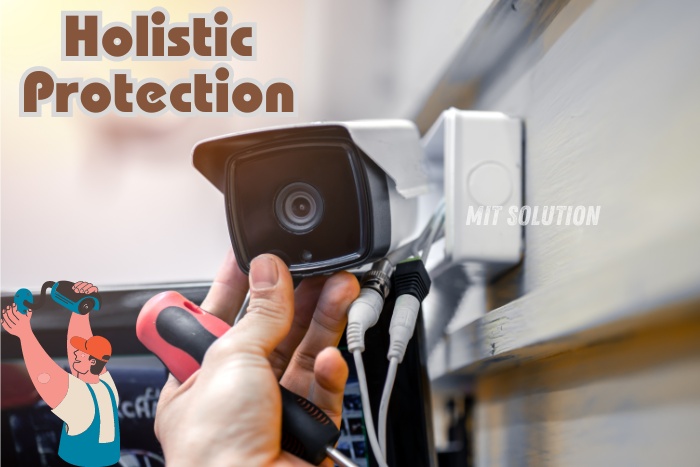 A professional installing a CCTV camera on a building exterior, highlighting holistic protection solutions provided by MIT Solution in Dindigul, Tamil Nadu. The caption 'Holistic Protection' emphasizes the comprehensive security services and advanced technology offered by MIT Solution