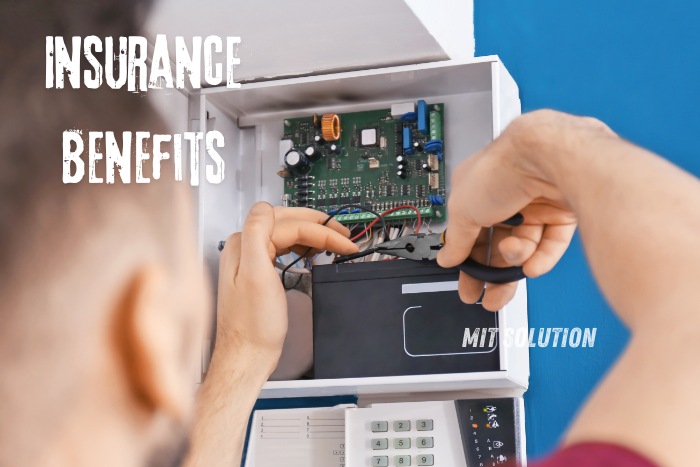 Close-up of a technician working on the internal components of a security alarm system, demonstrating the professional installation services provided by MIT Solution in Dindigul. The image highlights the 'Insurance Benefits' text, emphasizing the potential reduction in insurance premiums for businesses and homeowners who invest in comprehensive security systems